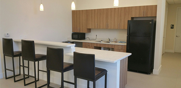 Kitchen with bar stool seating, white counter tops, wood cabinetry, and black appliances.